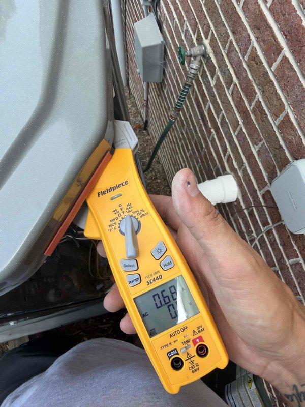 Responded to no-cooling complaint on upper floor heat pump system. Upon arrival, performed electrical diagnostics at outdoor unit using digital multimeter. Measured voltage and amperage readings at condensing unit to verify proper electrical supply and component operation. Initial readings indicated potential electrical issue requiring further troubleshooting. Tested multiple electrical circuits and connections at exterior unit mounted on brick wall to isolate root cause of system failure.