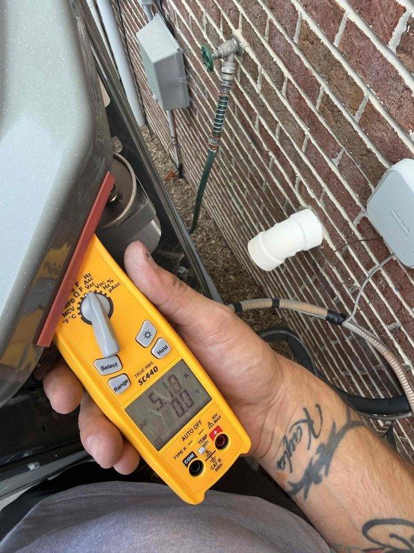Responded to no-cooling complaint on upper floor heat pump system. Upon arrival, performed electrical diagnostics at outdoor unit using digital multimeter. Measured voltage and amperage readings at condensing unit to verify proper electrical supply and component operation. Initial readings indicated potential electrical issue requiring further troubleshooting. Tested multiple electrical circuits and connections at exterior unit mounted on brick wall to isolate root cause of system failure.