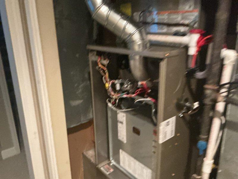 Completed full HVAC system installation in residential utility room, including Carrier furnace and air handler assembly. Installed gray metal furnace cabinet with integrated digital LED display and control panel, mounted metallic air handler unit above furnace, and established all electrical connections with proper color-coded control wiring. Routed and secured flexible ductwork from air handler, installed white PVC condensate drainage and venting piping per manufacturer specifications for high-efficiency system operation. Verified all manufacturer labels and specification plates properly affixed to equipment, confirmed digital display functionality, and ensured all utility connections properly secured and operational.