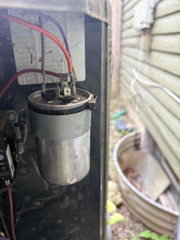 Completed scheduled cooling maintenance on residential air conditioning system. Performed comprehensive inspection of outdoor condensing unit, including visual assessment of capacitor which showed signs of age with corrosion present on electrical terminals and weathering on housing. Utilized Fieldpiece SC640 clamp meter to test capacitor performance, recording microfarad reading of 9.42. Inspected electrical connections, noting red and purple wires connected to capacitor terminals with visible oxidation typical of outdoor exposure. Evaluated overall unit condition, documenting accumulated dirt and grime on interior components and chassis. System operational at time of service completion.