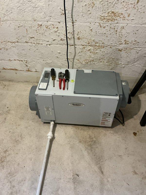 Returned to complete installation of blower assembly for Aprilaire dehumidifier unit in basement utility area. Successfully installed blower motor with mounting bracket, connected electrical wiring with proper wire nuts, and verified condensate drain line connection. Unit mounted securely to concrete block wall with all ductwork ports accessible for proper airflow distribution.