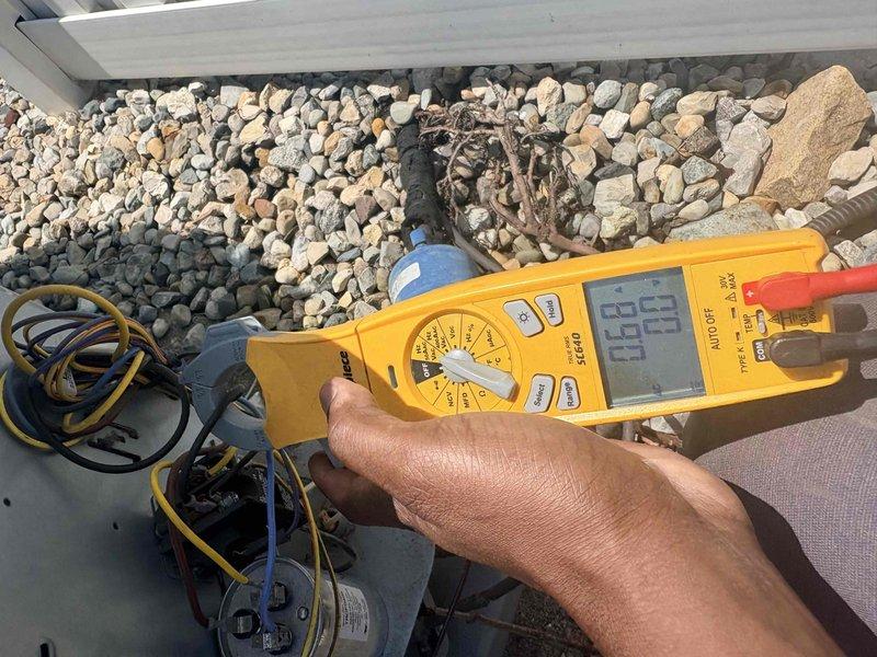 Completed comprehensive air conditioning tune-up on Carrier outdoor condensing unit. Performed electrical diagnostics using digital multimeter to verify capacitor function and electrical connections, inspected condenser coil and fan assembly, and confirmed proper system operation. Unit found in satisfactory condition with all components functioning within normal parameters.