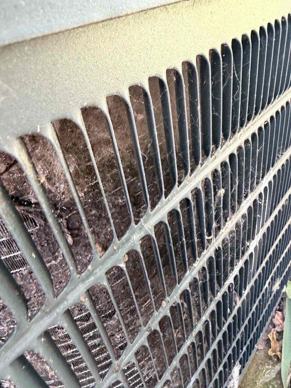 Responded to no cooling complaint on unit less than 10 years old that had been cycling intermittently with visible frost accumulation on evaporator coil. Upon inspection, found outdoor condenser coil heavily contaminated with dirt, dust, and debris buildup restricting airflow, which caused reduced system capacity and evaporator freezing. Documented condition of condenser unit showing significant maintenance neglect with substantial contamination between cooling fins and surrounding landscaping encroachment.