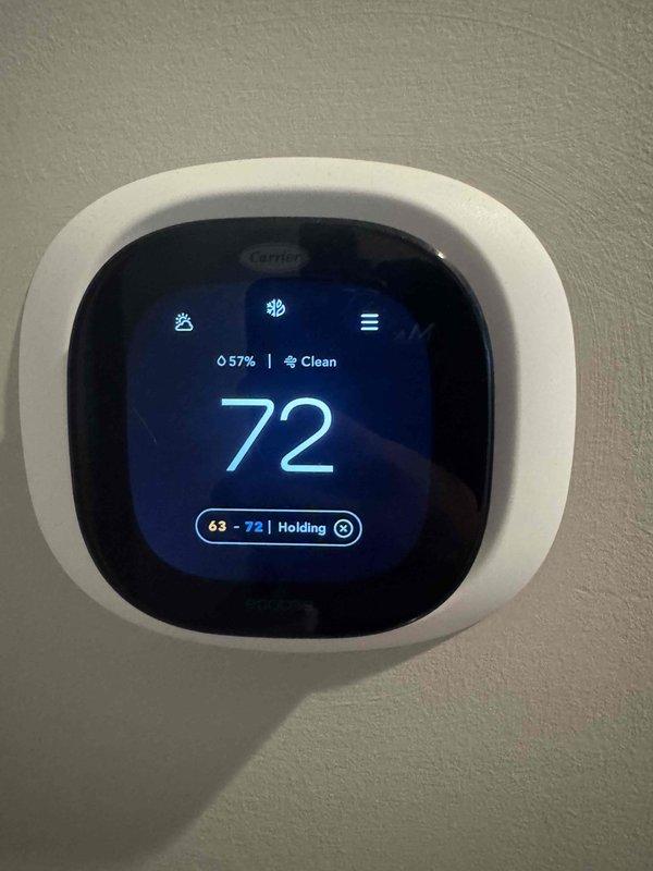 Completed comprehensive Super Tune-Up service on residential HVAC system. Performed electrical diagnostics using digital multimeter to verify proper voltage and amperage at the air handler's wiring compartment, confirming all electrical connections were secure and within manufacturer specifications. Verified Carrier thermostat operation showing system maintaining 72°F setpoint with hold function active and 57% humidity level displayed; confirmed thermostat communication and control functions operating correctly.