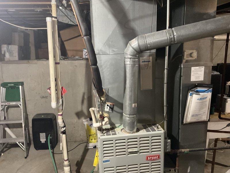 Completed HVAC system replacement estimate and site assessment for residential property. Evaluated existing Bryant furnace/air handler unit, associated ductwork, PVC venting system, and condensate drainage components in basement mechanical room. Documented current equipment configuration including furnace placement, metallic ductwork routing with multiple elbows, vertical PVC vent piping with proper strapping, and electrical wiring layout. Photographed equipment conditions and surrounding utility infrastructure to support replacement proposal.
