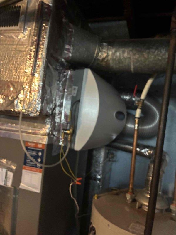 Completed installation of new bypass humidifier and REME HALO air purification system on existing HVAC ductwork. Both units were properly mounted, connected to supply ductwork, and wired according to manufacturer specifications, with the REME HALO displaying operational status and the humidifier integrated into the forced air system with appropriate water supply connections.