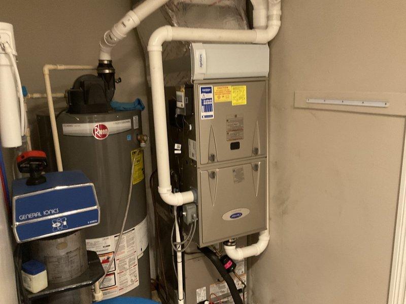 Returned to complete HVAC system installation in residential utility room. Finalized installation of Carrier furnace unit with complete PVC venting and ductwork connections, verified proper integration with existing water heater and pressure tank system. All equipment tested and operational, installation documented with photos showing completed mechanical room setup with proper clearances and code-compliant piping configurations.