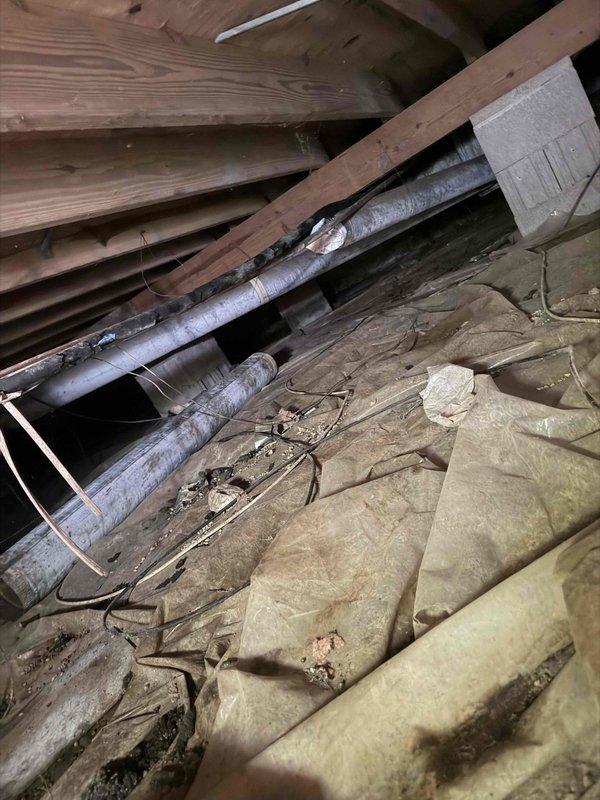 Responded to service call for fallen ductwork in crawl space and water intrusion through furnace vent pipe. Inspected crawl space and confirmed section of ductwork had become disconnected from supports. Examined roof-mounted furnace vent stack and flashing, which showed significant rust, corrosion, and deterioration allowing rainwater to enter the system and drip into the furnace cabinet. Documented conditions with photos for repair recommendations and provided estimate for ductwork resecuring and vent pipe flashing replacement to prevent further water damage.