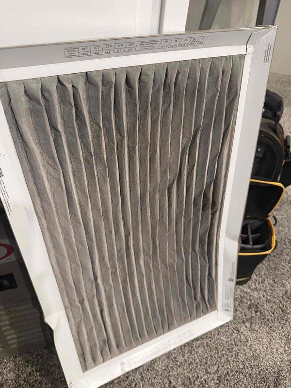 Responded to request for IAQ estimate due to elevated humidity levels reading 75% on thermostat and concerns about pre-existing programming from previous homeowners. Performed site assessment of basement mechanical area and existing HVAC system, documenting current conditions including sump pump drainage configuration, exposed utility areas, and air filtration equipment. Inspected existing air filter showing moderate dust accumulation and particulate matter buildup, evaluated overall system accessibility and existing infrastructure for potential humidity control solutions and equipment upgrades.