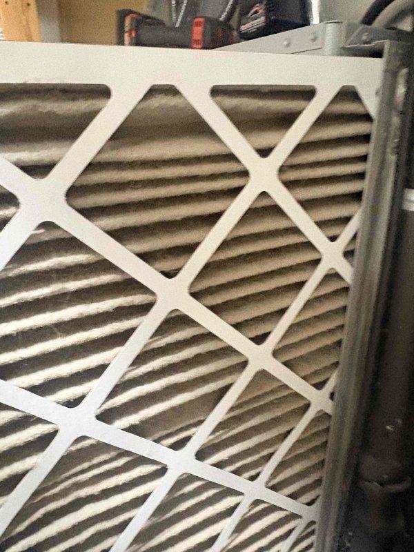 Completed comprehensive tune-up on residential cooling system. Inspected air filter showing significant dust accumulation and discoloration in pleated media, indicating proper filtration but need for replacement. Performed electrical diagnostics using digital multimeter, recording amperage draw of 0.21A and voltage reading of 0.1V AC to verify system performance and component operation within manufacturer specifications.