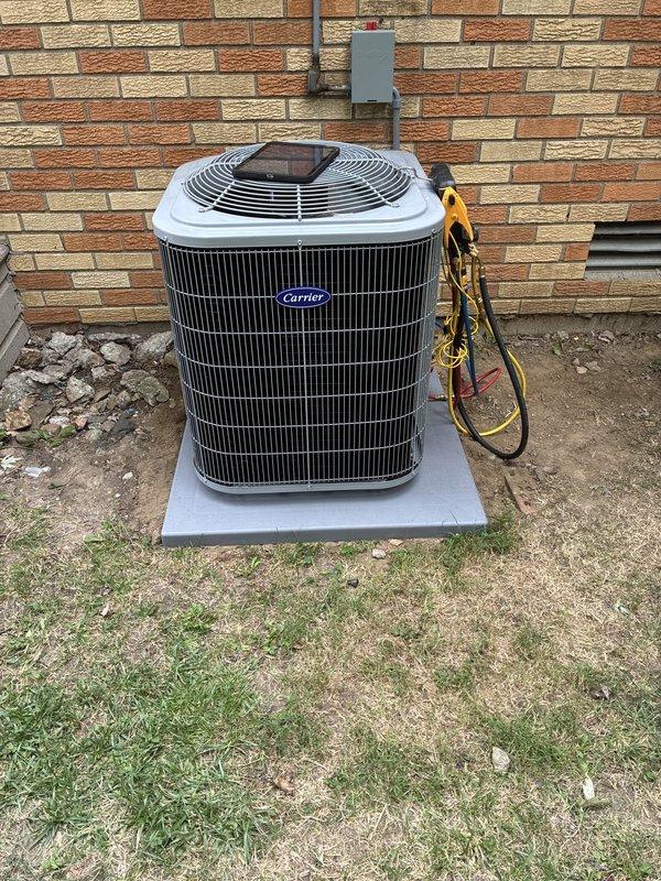 Completed full system installation including Carrier outdoor condensing unit and indoor air handler section (model CHNVA2417XMAABAA). Unit positioned on concrete pad with proper electrical disconnect and refrigerant line connections established. System charged with R-454B refrigerant to manufacturer specifications, pressure tested, and verified operational with gauge set confirming proper system pressures and performance.