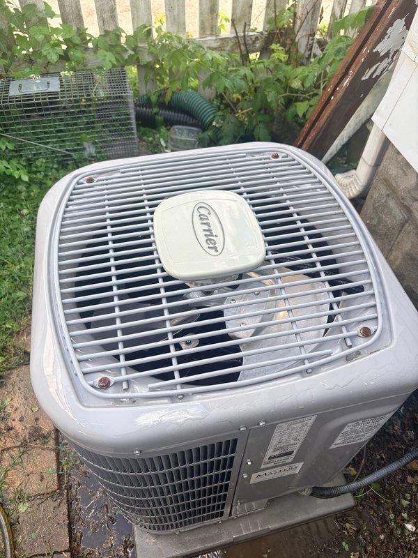 Responded to service call for Carrier outdoor condenser unit experiencing rattling noise. Performed complete cooling system maintenance inspection on older model unit. Upon arrival, inspected condenser unit exterior condition, noted weathering consistent with age, and evaluated operational status. Examined condenser fan motor and blade assembly for source of reported rattling noise. Observed motor shaft and mechanical components during operation to identify any loose hardware, bearing wear, or imbalance issues. Verified fan motor rotation and checked for debris or foreign objects within fan shroud that could cause noise. Inspected condenser coil condition, noting outdoor exposure to vegetation and environmental elements. Completed standard maintenance protocol including operational testing of all system components. Unit found operational and suitable for continued service following inspection and maintenance procedures.