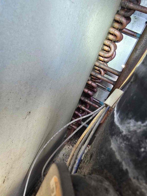 Responded to no cooling complaint on Bryant rooftop package unit. Upon arrival, inspected refrigerant lines and found severely oxidized copper tubing with significant discoloration indicating moisture exposure and possible previous leak history. Observed deteriorated coil condition in confined mechanical space with evidence of environmental damage to piping system. Documented equipment condition with photos showing compromised refrigerant lines and aged components requiring attention to restore proper cooling operation.