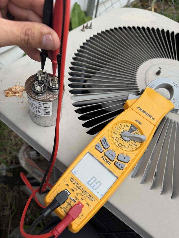 Responded to no cooling call with reported buzzing noise from outdoor unit. Upon arrival, performed diagnostic evaluation of air conditioning system. Inspected electrical components and tested dual-run capacitor using digital multimeter. Found capacitor failed and unable to hold proper charge, preventing compressor and condenser fan motor from starting. Buzzing noise confirmed as compressor attempting to start with insufficient capacitance. Replaced failed capacitor with new dual-run capacitor rated at 25+5 microfarads. Verified proper electrical connections to compressor and fan motor terminals. Cycled system on and tested operation. Compressor and condenser fan motor started successfully without abnormal noise. Confirmed adequate cooling performance and proper amp draw on both motors. System restored to normal operation.