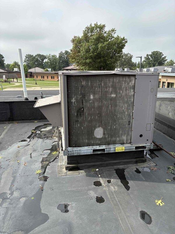 Conducted site evaluation of existing Carrier rooftop package unit on commercial property to provide replacement estimate. Unit exhibited significant deterioration including heavily soiled condenser coil with accumulated grime and debris, extensive rust staining and corrosion on evaporator coil section, and compromised condensate drainage with visible moisture damage patterns. Measured existing unit dimensions at approximately 48 inches to ensure proper replacement sizing. Noted deteriorated roofing membrane beneath unit with water damage and multiple penetrations requiring coordination during changeout. Documented equipment condition through photographic evidence showing corroded components, clogged drain pan with organic debris buildup, and weathered refrigerant lines. Prepared comprehensive replacement proposal for new rooftop package unit installation including necessary curb modifications and roof membrane repairs at equipment location.