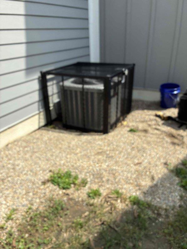 # HVAC Maintenance Summary

Completed scheduled preventive maintenance on residential cooling system. Performed comprehensive inspection of outdoor condenser unit, verified electrical measurements with multimeter showing 0.7 AAC reading, and documented equipment condition through photographic records.

# Detailed Work Performed

Arrived on-site to perform routine cooling system maintenance on single outdoor condensing unit. The equipment was housed in a protective black metal cage mounted on concrete pad against building exterior.

**Inspection and Testing:**
Conducted visual inspection of condenser unit and surrounding area. Noted vegetation growth near equipment pad requiring customer attention for proper airflow clearance. Performed electrical diagnostics using calibrated digital multimeter to verify system amperage and operational parameters. Recorded electrical reading of 0.7 AAC during testing phase, indicating system operating within normal parameters.

**Equipment Assessment:**