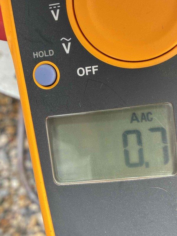 # HVAC Maintenance Summary

Completed scheduled preventive maintenance on residential cooling system. Performed comprehensive inspection of outdoor condenser unit, verified electrical measurements with multimeter showing 0.7 AAC reading, and documented equipment condition through photographic records.

# Detailed Work Performed

Arrived on-site to perform routine cooling system maintenance on single outdoor condensing unit. The equipment was housed in a protective black metal cage mounted on concrete pad against building exterior.

**Inspection and Testing:**
Conducted visual inspection of condenser unit and surrounding area. Noted vegetation growth near equipment pad requiring customer attention for proper airflow clearance. Performed electrical diagnostics using calibrated digital multimeter to verify system amperage and operational parameters. Recorded electrical reading of 0.7 AAC during testing phase, indicating system operating within normal parameters.

**Equipment Assessment:**