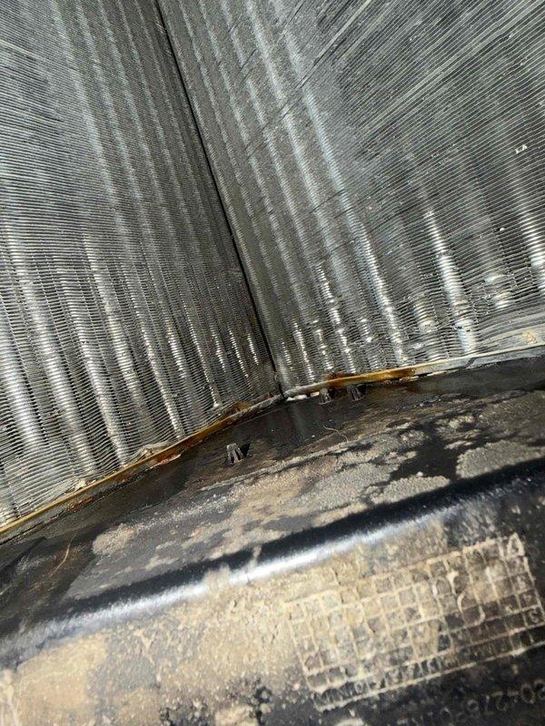 Responded to callback for system freezing issue. Upon arrival, performed thorough inspection of air handling unit and evaporator coil assembly. Found evaporator coil with significant dust and debris accumulation on fins and surrounding components. Drain pan showed heavy buildup of dirt and contaminants, indicating restricted airflow as primary cause of freeze-up condition. Documented coil condition with photos showing corroded areas at coil junction and substantial fouling throughout finned surfaces. Explained findings to occupant regarding need for professional coil cleaning to restore proper airflow and prevent future freezing. System requires coil cleaning service to resolve underlying issue and restore normal operation.