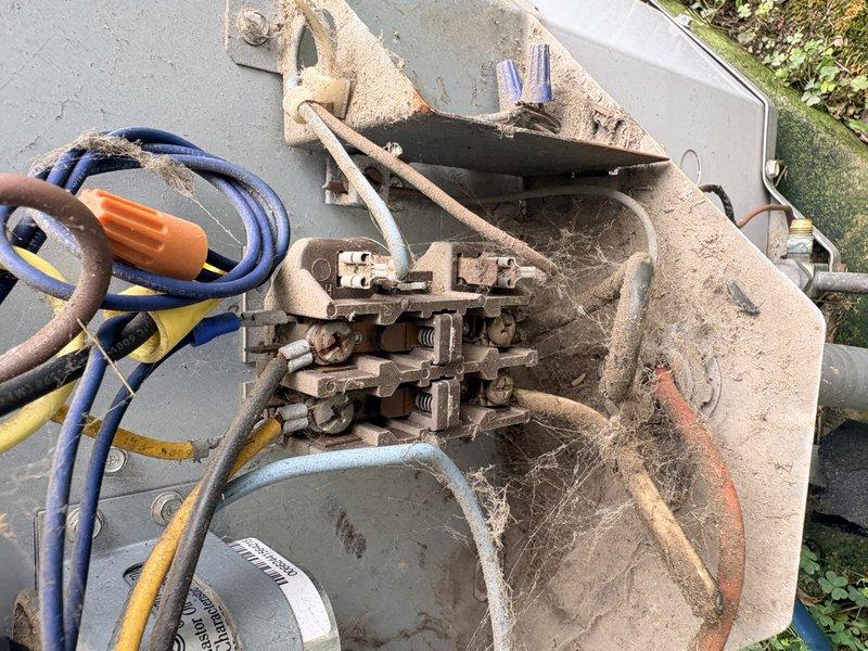 Responded to no cooling complaint at warehouse facility and inspected rooftop HVAC unit. Upon examination, discovered severely corroded electrical terminal block with extensive rust on brass terminals, compromised wire connections, and heavy cobweb and debris accumulation throughout electrical compartment. Equipment showed signs of prolonged exposure to elements without maintenance, with oxidized connections and deteriorated wiring presenting safety concerns and preventing proper unit operation.