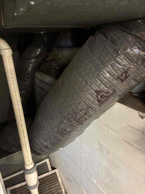 Completed system replacement estimate and site assessment for full HVAC system changeout. Documented existing equipment installation in attic space, including cylindrical supply ductwork with reflective insulation, flexible return ducts, PVC condensate drainage lines, and air filtration components. Measured and photographed existing duct materials and connections, noting Polyken foil mastic tape applications on duct joints. Verified confined workspace dimensions and equipment access points to ensure proper planning for new system installation.