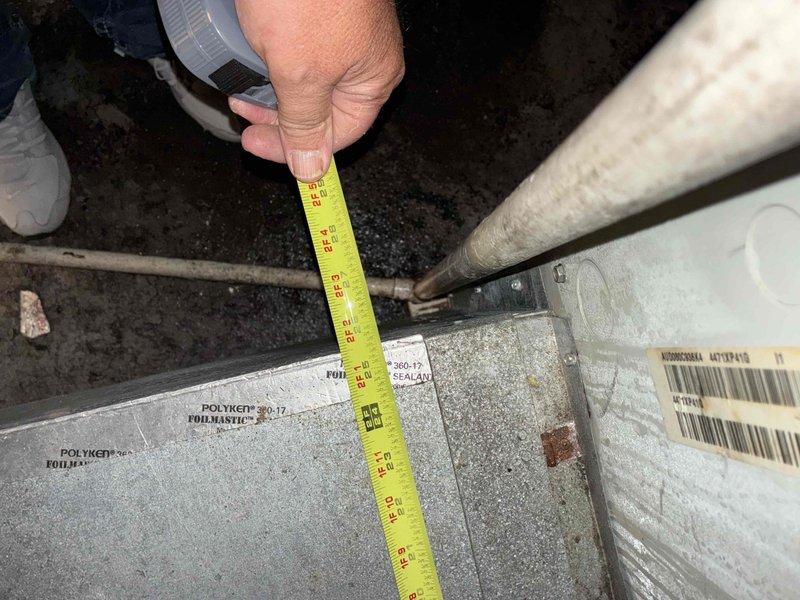 Completed system replacement estimate and site assessment for full HVAC system changeout. Documented existing equipment installation in attic space, including cylindrical supply ductwork with reflective insulation, flexible return ducts, PVC condensate drainage lines, and air filtration components. Measured and photographed existing duct materials and connections, noting Polyken foil mastic tape applications on duct joints. Verified confined workspace dimensions and equipment access points to ensure proper planning for new system installation.