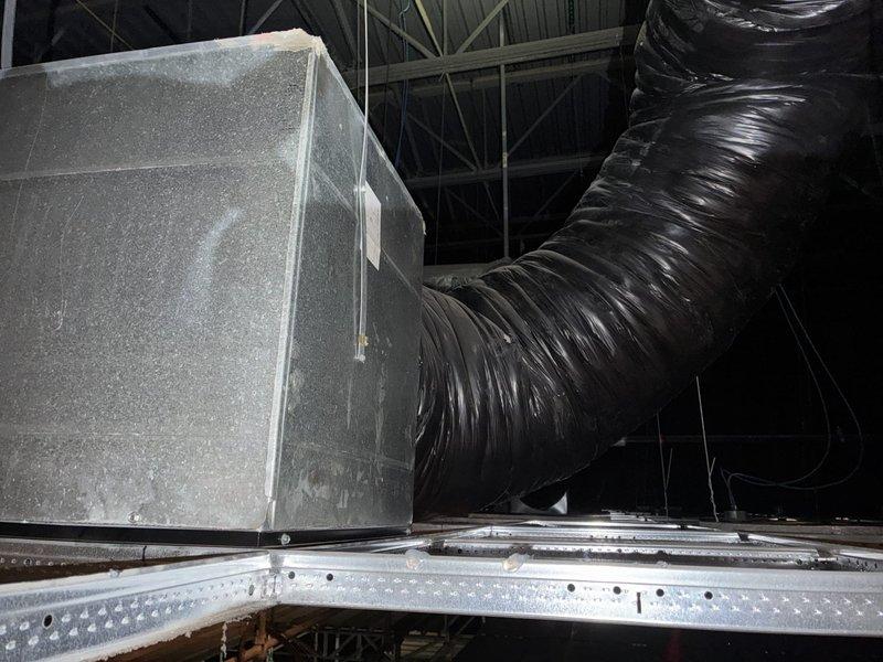 Completed HVAC ductwork installation in commercial auditorium setting, replacing both return air boxes positioned beneath curved screen area in accordance with architectural specifications and building codes. Modified two supply air drops in ceiling area at front of auditorium to ensure proper airflow distribution and system performance. All work performed utilizing pre-assembled scaffolding to access elevated ceiling spaces, with installation of flexible ductwork, metal air handler connections, and galvanized support brackets to secure system components per industry standards.
