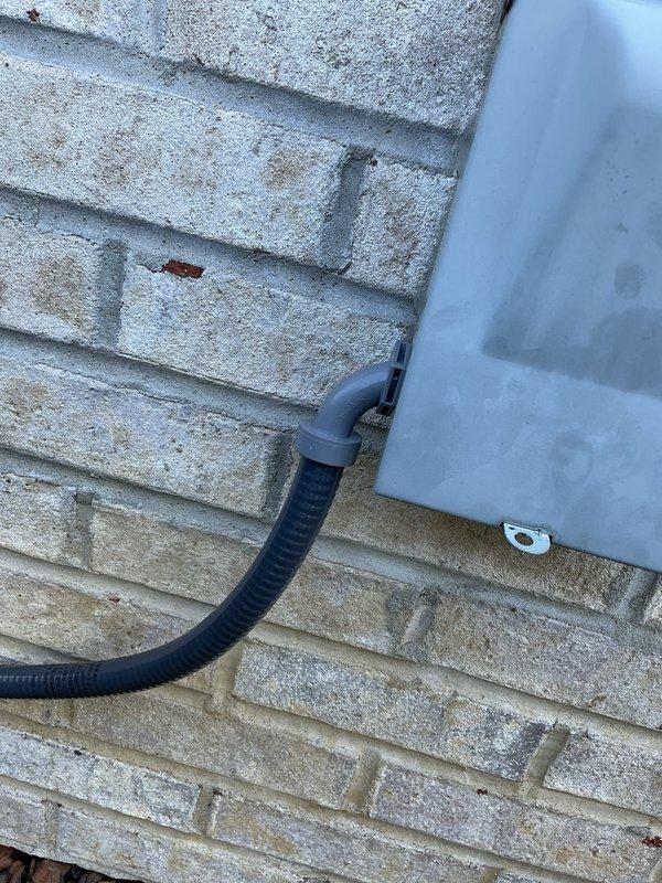 Removed and replaced deteriorated high voltage electrical wiring and protective conduit on outdoor HVAC unit. Installed new electrical wiring with black flexible conduit properly secured to building exterior and connected to unit. Verified all electrical connections were tight and properly terminated, then performed system operational test to confirm proper function and safety compliance.