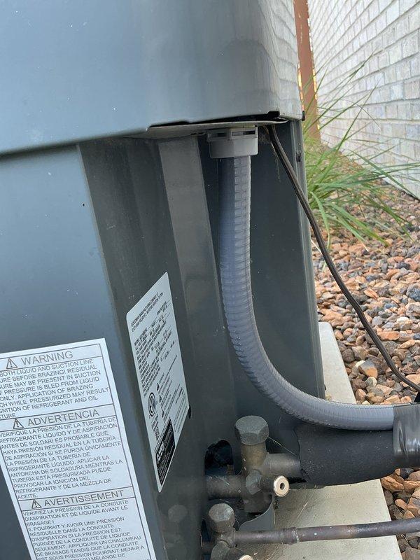 Removed and replaced deteriorated high voltage electrical wiring and protective conduit on outdoor HVAC unit. Installed new electrical wiring with black flexible conduit properly secured to building exterior and connected to unit. Verified all electrical connections were tight and properly terminated, then performed system operational test to confirm proper function and safety compliance.