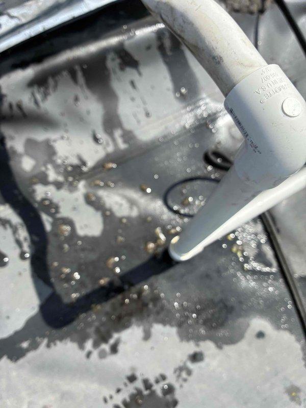Responded to report of water leaking from rooftop HVAC unit. Upon inspection, found excessive condensation and moisture accumulation in drain pan with water pooling around condensate drainage components. Examined white PVC condensate drain line and surrounding system components. Documented moisture buildup patterns and drainage system condition with photographic evidence for diagnostic evaluation.