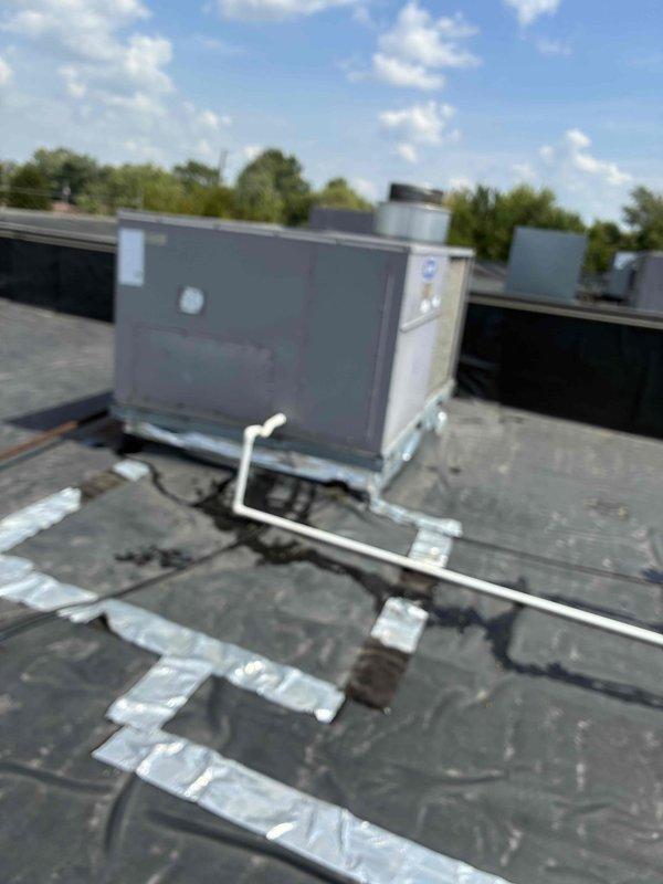 Responded to report of water leaking from rooftop HVAC unit. Upon inspection, found excessive condensation and moisture accumulation in drain pan with water pooling around condensate drainage components. Examined white PVC condensate drain line and surrounding system components. Documented moisture buildup patterns and drainage system condition with photographic evidence for diagnostic evaluation.