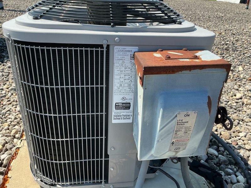 Conducted initial site survey to collect equipment information for commercial maintenance agreement proposal. Documented multiple rooftop HVAC units including several RTUs and a cylindrical air conditioning condenser with vertical fin design, noting equipment specifications, manufacturer data plates, and electrical disconnect components. Photographed all units to assess current condition and compile inventory for maintenance agreement quotation.