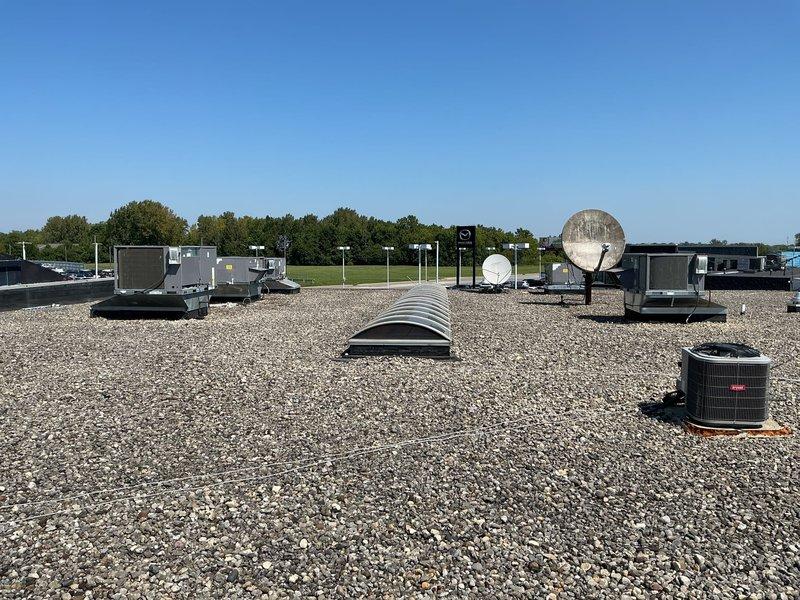 Conducted initial site survey to collect equipment information for commercial maintenance agreement proposal. Documented multiple rooftop HVAC units including several RTUs and a cylindrical air conditioning condenser with vertical fin design, noting equipment specifications, manufacturer data plates, and electrical disconnect components. Photographed all units to assess current condition and compile inventory for maintenance agreement quotation.
