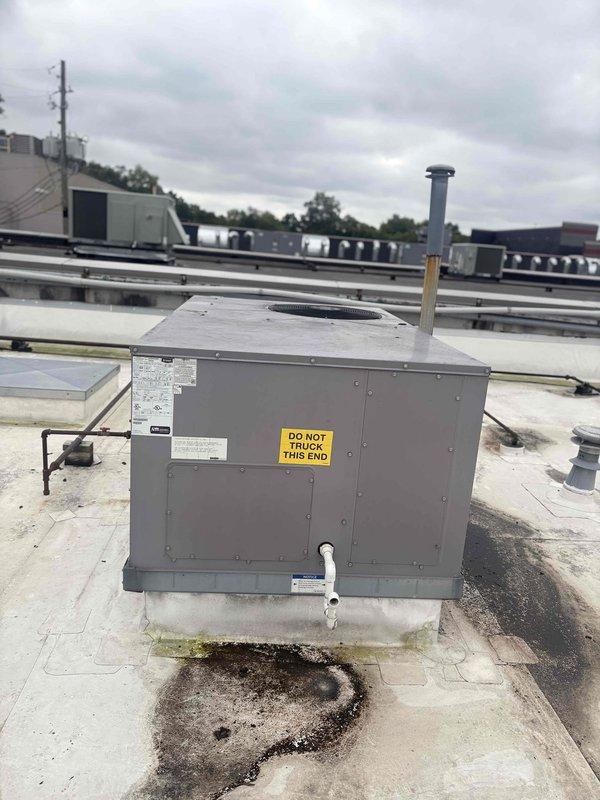 Conducted site survey of commercial rooftop HVAC equipment to document unit specifications and assess condition for maintenance plan proposal. Accessed and photographed rooftop unit mounted on concrete pad, recording manufacturer information, model data, and warning labels from equipment nameplate. Inspected filter assembly and documented equipment configuration, noting surface staining on roof deck near unit base indicating potential drainage concerns that should be monitored during future service visits.
