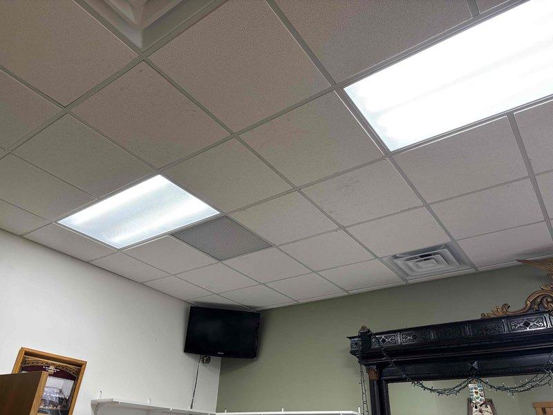 Returned to site to complete miscellaneous work items. Accessed ceiling space via ladder to inspect and photograph drop ceiling system, fluorescent lighting fixtures, and ventilation components. Documented ceiling tile grid layout, recessed light panels, and skylight panel installation for service records.