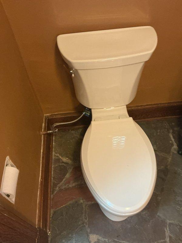 Completed installation of standard two-piece white porcelain toilet in bathroom corner location. Connected water supply line to tank, secured unit to floor flange, and verified proper flush operation and bowl refill. Toilet is fully operational with no leaks detected at supply connection or base seal.
