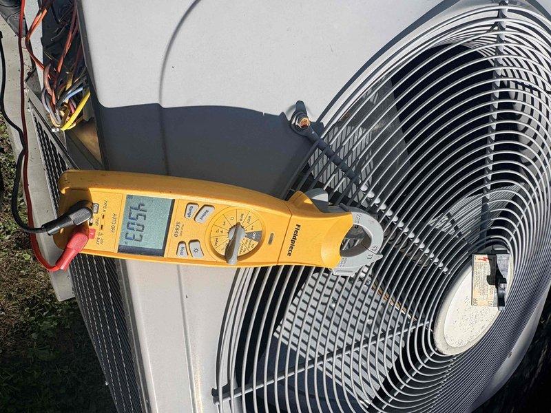 Completed prepaid heating maintenance on residential HVAC system. Performed comprehensive system diagnostics including electrical measurements using digital multimeter, verified proper voltage and amperage readings at outdoor unit, and inspected condenser coil condition. All components operating within normal parameters with system reading 60.5 Hz frequency, refrigerant lines properly connected, and unit cycling correctly.