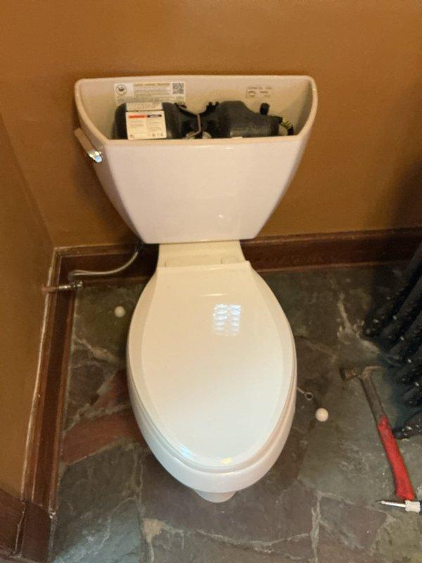 Conducted comprehensive site visit to assess toilet installation and related plumbing systems. Inspected toilet unit with exposed tank mechanism, evaluated water supply line connection, and examined basement plumbing infrastructure including shut-off valve and supply piping. Documented existing conditions of toilet installation in progress on unfinished flooring and verified proper routing of water supply lines from basement to fixture location.