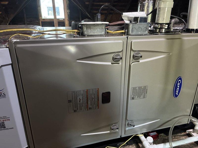 Completed installation of Carrier 59TP7A100V21--20 Performance 97 Series two-stage gas furnace with 100,000 BTU heating capacity in attic space, replacing existing 90% efficiency unit. Reconfigured and installed new ductwork with zoning system, insulated flue and drain lines, installed electrical junction boxes and conduit, and properly routed all PVC condensate drainage. All components installed per manufacturer specifications with AHRI matchup certification 215722132/216012690, achieving 16.5 SEER2 and HSPF2 rating of 8.