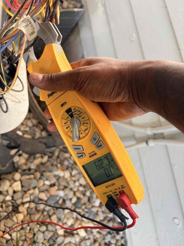 Completed preventative maintenance on heating system. Performed electrical diagnostics using clamp meter on outdoor unit wiring, recording voltage and amperage readings of 62.9V and 0.0A on multi-conductor bundle. Tested indoor air handler electrical system, measuring 4.13A current draw with 0.0V secondary reading. Inspected heat exchanger coil and verified all electrical connections secure. System operating within normal parameters.