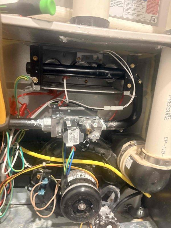 Responded to a no-heat call on a gas furnace less than 10 years old and inspected the burner assembly, gas valve, draft inducer assembly, and associated wiring. Found corrosion and residue buildup on the gas valve body and fittings, along with soot discoloration around the burner components, with no evidence of frost, ice, or major rust. Documented the findings with photos for the service record.