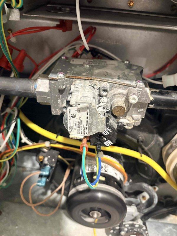 Responded to a no-heat call on a gas furnace less than 10 years old and inspected the burner assembly, gas valve, draft inducer assembly, and associated wiring. Found corrosion and residue buildup on the gas valve body and fittings, along with soot discoloration around the burner components, with no evidence of frost, ice, or major rust. Documented the findings with photos for the service record.