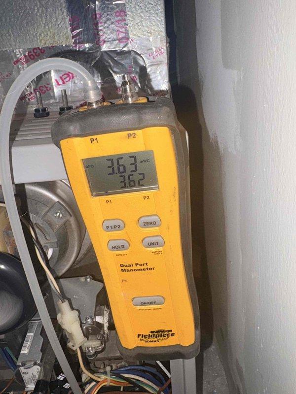 Performed a heating tune-up on the furnace, including measurement of static pressure across the system with a dual port manometer (approximately 3.6 inWC), indicating elevated static pressure that may be restricting airflow. Inspected the blower assembly and found moderate dust and grime buildup on the blower wheel blades, with scuffing and wear on the hub, and verified the wiring harness and internal components showed no obvious damage, rust, or frost.