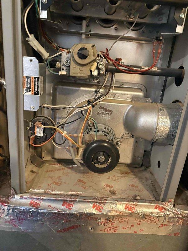 Performed a furnace tune-up with the access panel removed, inspecting the burner assembly, heat exchanger openings, gas valve and manifold, inducer motor, flue elbow, pressure switch, and wiring harnesses. Checked electrical operation with a clamp meter and found no visible damage, rust, or cracks, with only light dust and debris in the cabinet.