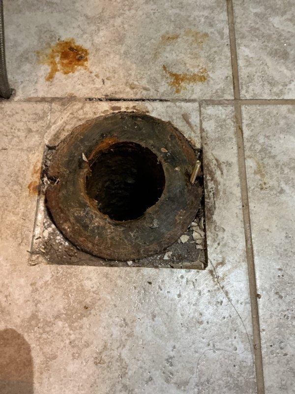 Responded to toilet leak issue requiring service. Removed existing toilet to reveal heavily corroded floor flange with rust damage to surrounding tile. Installed new wax ring and replaced damaged flange, then reset toilet and sealed base to prevent future leakage.