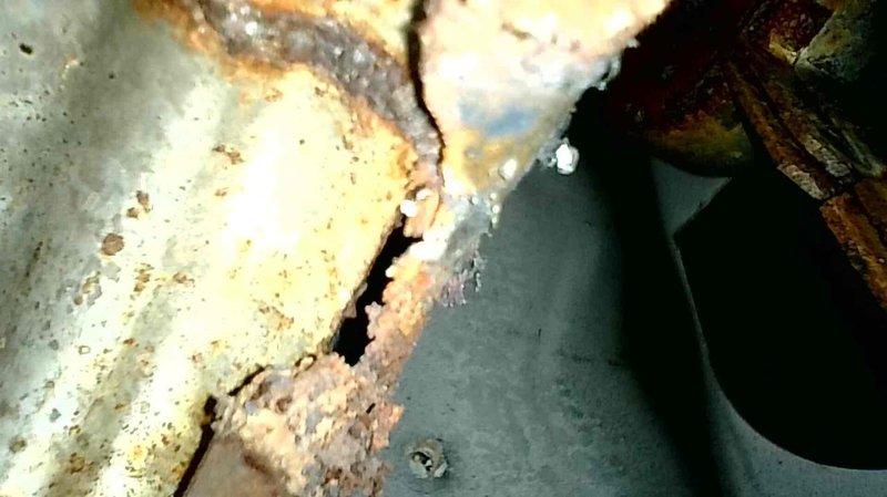 Responded to service call for an A/C system that wasn't running properly with fan continuously operating. Determined roll out switch was tripped, causing the continuous fan operation and preventing cooling function. Reset roll out switch which immediately restored normal A/C operation. Inspection with camera revealed separations in two burner inlets creating oxygen leaks, causing excessive combustion issues and soot buildup. Heat exchanger showed significant corrosion with visible cracks. Unit was tagged for safety and customer was informed about necessary heat exchanger replacement.