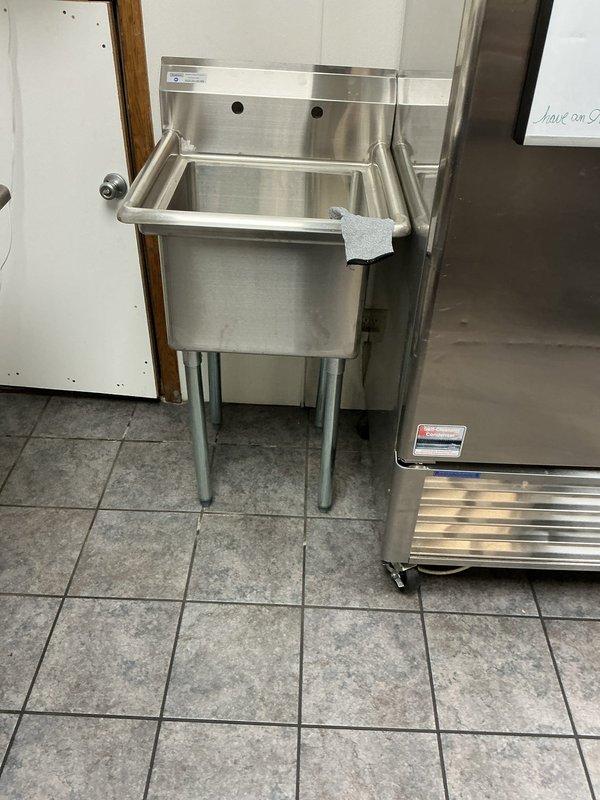 Completed site visit to estimate installation of customer-supplied commercial produce sink. Discovered installation challenges including lack of accessible drainage and water supply lines, with only limited access through tight quarters behind wall. Documented existing space and utility access points to develop comprehensive installation plan.