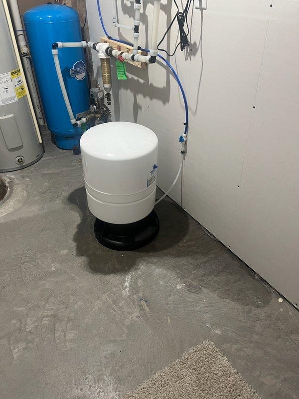 Diagnosed and repaired a leak on previously installed 8-12 R/O system where customer reported water on floor around unit and no water production. Inspection revealed the RO storage tank was leaking due to a split 3/4" plastic 90-degree fitting. Replaced the damaged plastic fitting with a more durable brass 90-degree fitting to resolve the issue and restore proper system operation.