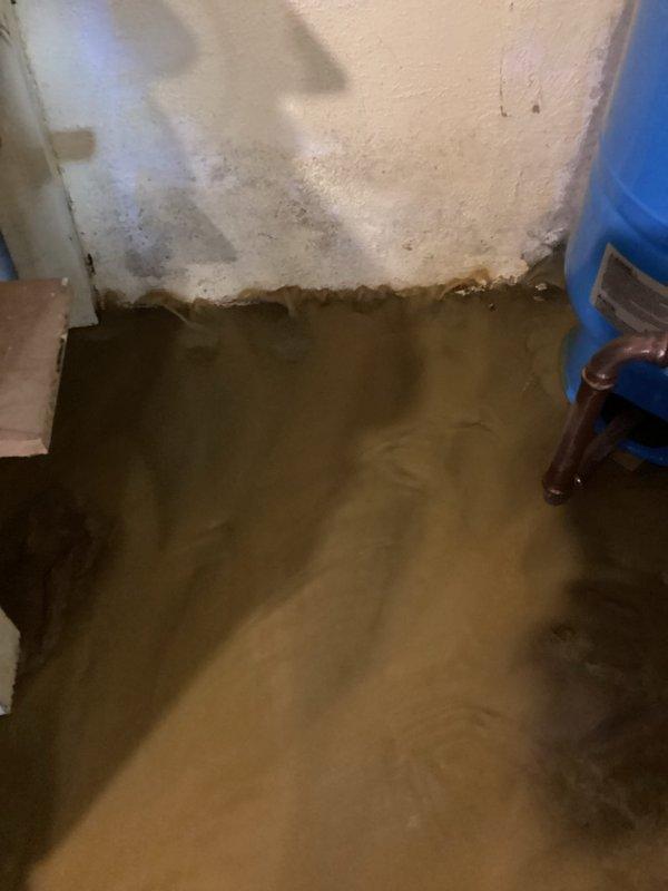 Responded to emergency water intrusion call for basement flooding. Upon inspection, identified failed galvanized main water line beneath basement floor as source of leak. Observed approximately 2-3 inches of standing water throughout basement with visible wall damage. Customer referred to well company specialist for subsurface pipe replacement and remediation.