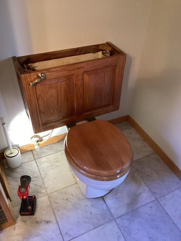 Replaced damaged toilet innards and installed new comfort height toilet due to leaking valve. Repaired toilet flange and installed on marble tile flooring, addressing water damage from previous leak.