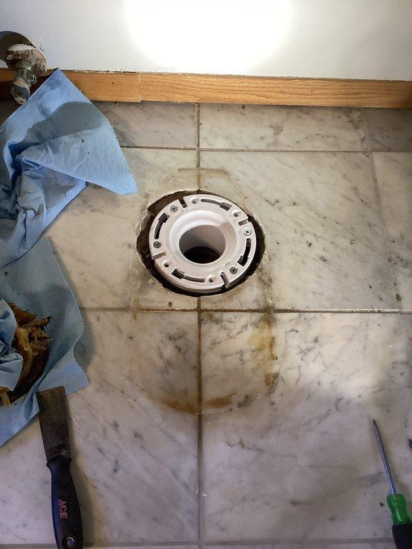 Replaced damaged toilet innards and installed new comfort height toilet due to leaking valve. Repaired toilet flange and installed on marble tile flooring, addressing water damage from previous leak.